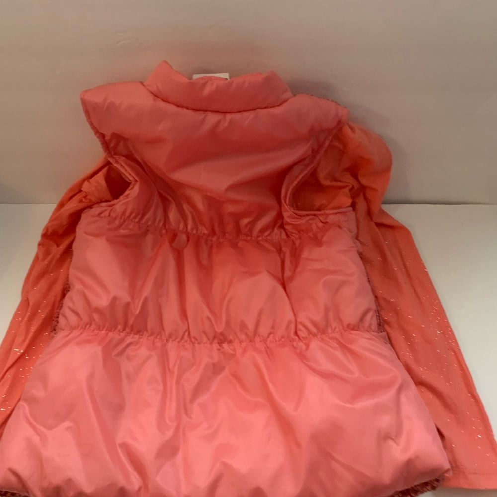 A two piece vest with long sleeve in a coral color the vest has a front zipper